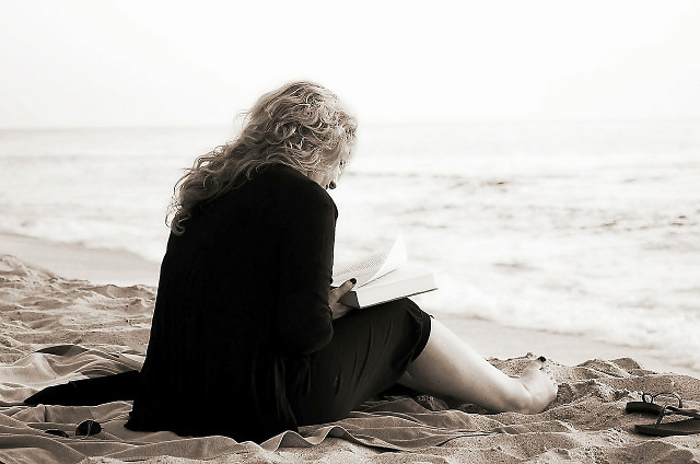 [Picture of woman on a beach reading a book